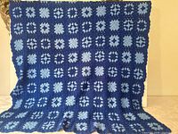 Full view of navy and light blue granny square afghan hanging