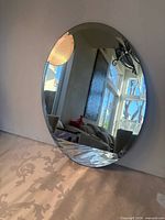 Front view of oval frameless mirror showing beveled edge and reflective surface
