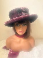 Mannequin head wearing burgundy velvet hat with feather trim