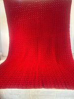 Full view of red crochet afghan draped to show size and pattern