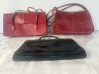 Front view of two red handbags and black clutch