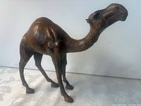 Profile view of wooden camel figurine showing head, neck and legs