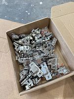 Box containing numerous chrome concealed cabinet hinges