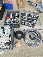 Overall view of totes with metal duct fittings, organizer drawers, PVC fittings, coiled tubing