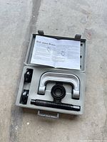 Open case showing entire kit: C-frame, screw, three adapters, instructions