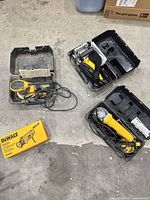 Group view of four DeWalt corded tools with three hard cases and one yellow box