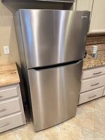 Front view of closed stainless steel Frigidaire top freezer refrigerator