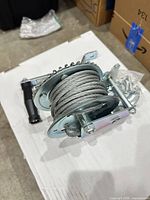 Winch coiled with steel cable and hardware bag visible