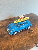 Front three-quarter view of the assembled blue LEGO Beetle with surfboard and cooler on roof rack
