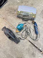 Group shot of three sanders, closed Dremel case and cords on floor