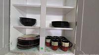Cabinet view showing stacks of bowls, plates and mugs