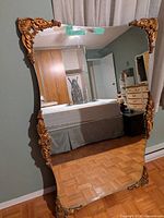 Full view of gold ornate rectangular mirror leaning against wall
