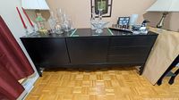 Front view of black sideboard showing cabinet doors left and three drawers right