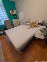 Full mattress on box spring with protector in place, surrounding accessories visible