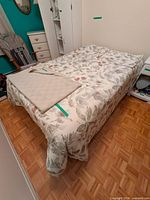 Bed with floral comforter, blanket on top