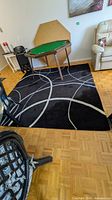 Full view of square black rug beneath table showing curved gray line pattern