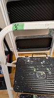Close view of top section and tread of ladder showing paint splatter and frame detail