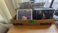 Box containing stack of standard jewel-case CDs; front cases show Elton John and Jason McCoy titles