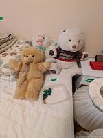 All three plush animals on bed with marbles container visible