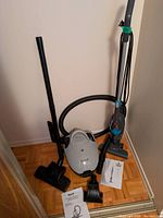 Both vacuums, hose, wand, heads and manuals grouped together