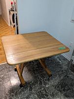 Table fully open showing square top surface and casters