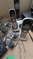 Two Uniden handsets on answering base and charging cradle with cords visible