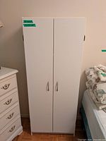 Front view of closed white cabinet showing two doors and handles