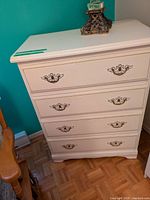 Front view of white four-drawer dresser with brass pulls