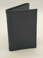 Front view of black Nike tri-fold wallet standing closed