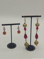 Overview of two pairs of dangling earrings on stands