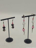 Both pairs of earrings displayed on stands showing overall designs and lengths