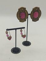 Both pairs of earrings on display stands for scale and overview