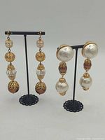 Both pairs of earrings displayed on stands