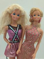 Both Barbie dolls standing side by side displaying outfits and hair