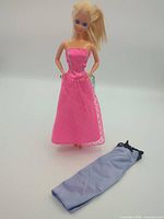 Full view of Barbie doll with pink gown and extra lavender garment laid in front