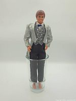 Front full-length view of 1968 Ken doll wearing silver tuxedo jacket and black pants
