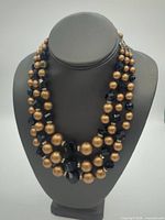 Full view of triple-strand gold and black beaded necklace on display bust