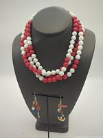 Necklace displayed on bust with earrings on stand