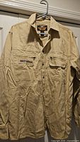 Front view of beige Harley-Davidson button shirt on hanger