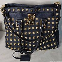 Front view showing gold studs, handles, strap, lock