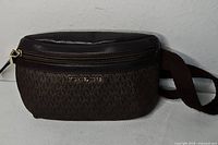 Front view of Michael Kors monogram fanny pack showing logo, zipper, leather trim