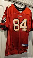 Front of red Reebok Buccaneers #84 jersey on hanger