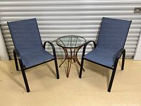 Two blue sling chairs and glass top side table