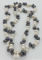 Full view of both strands showing white and dark baroque pearls and clasp