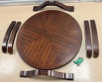 Top view of round tabletop, four curved legs, cross-braces, bolt bag