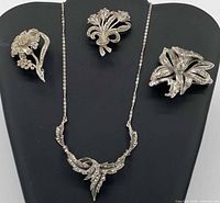 Group image of necklace and three brooches on display stand