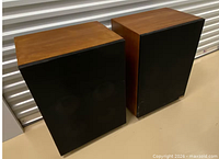 Front and side view of both speakers showing wood veneer and black grilles