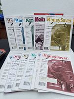 Front view of approximately eleven Canadian MoneySaver magazines showing assorted cover colours and topics