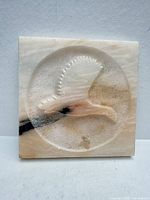 Front view of square marble plaque showing full bird carving