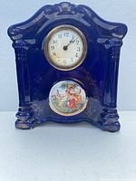 Front view showing clock face, cobalt glaze, columns, cherub insert